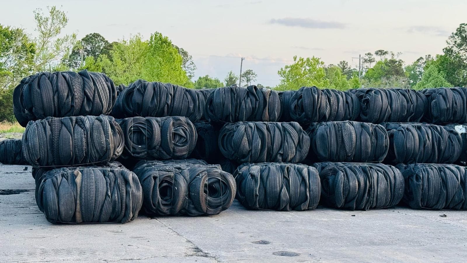 High-density baled scrap tires stacked at a ScraPack Solutions yard, ready for container loading